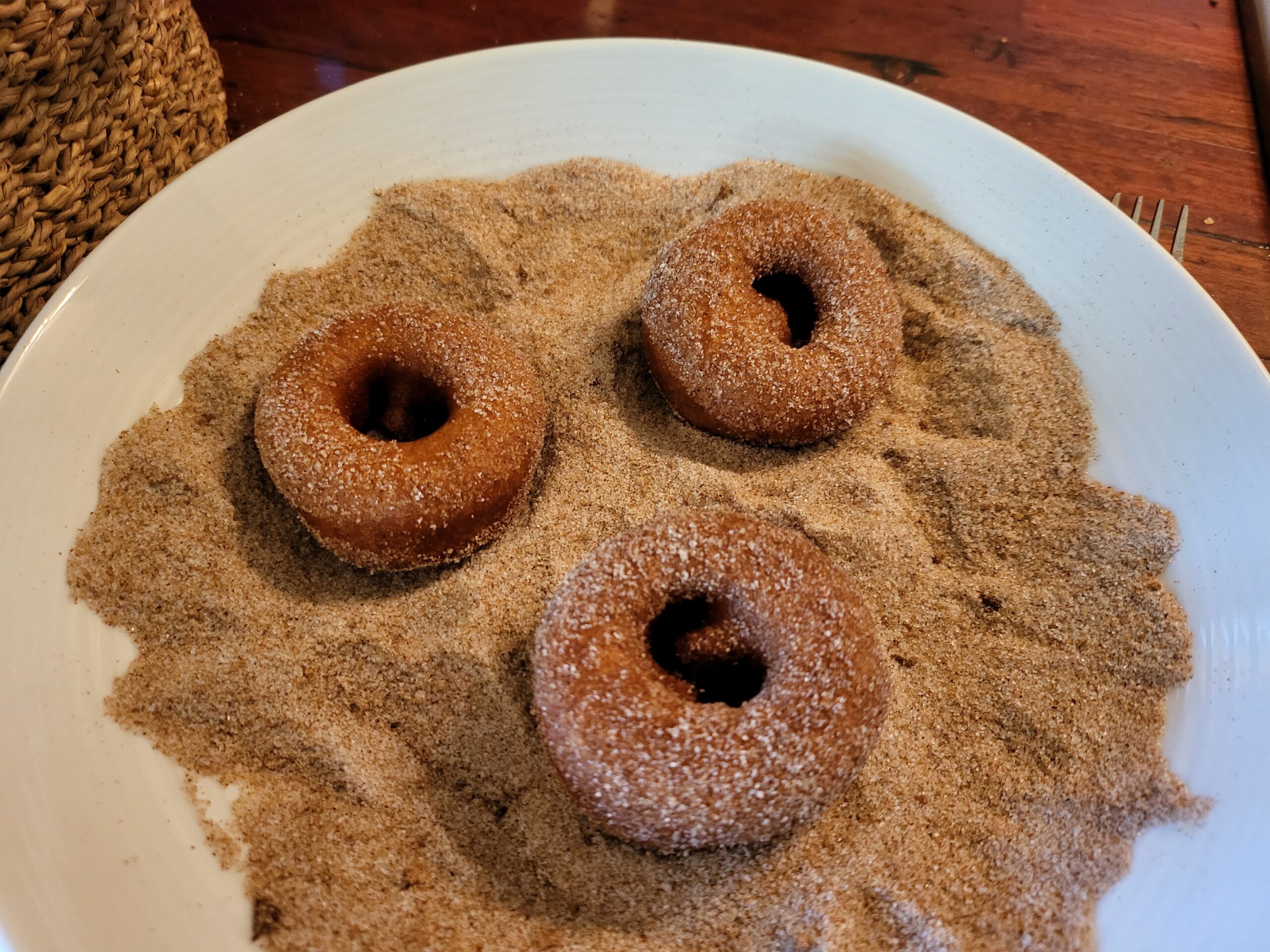 three ring donuts covered in sugar and cinnamon on a plate
